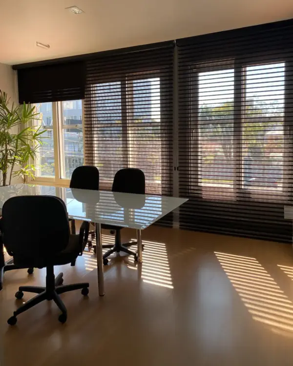 Cortina miragem preta instalada em sala de reuniões, com controle de luz natural e visual moderno.