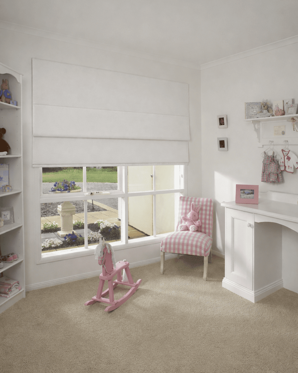 Cortina Romana Blackout Nápoles branca semiaberta em quarto de bebê, permitindo entrada suave de luz natural em ambiente residencial.