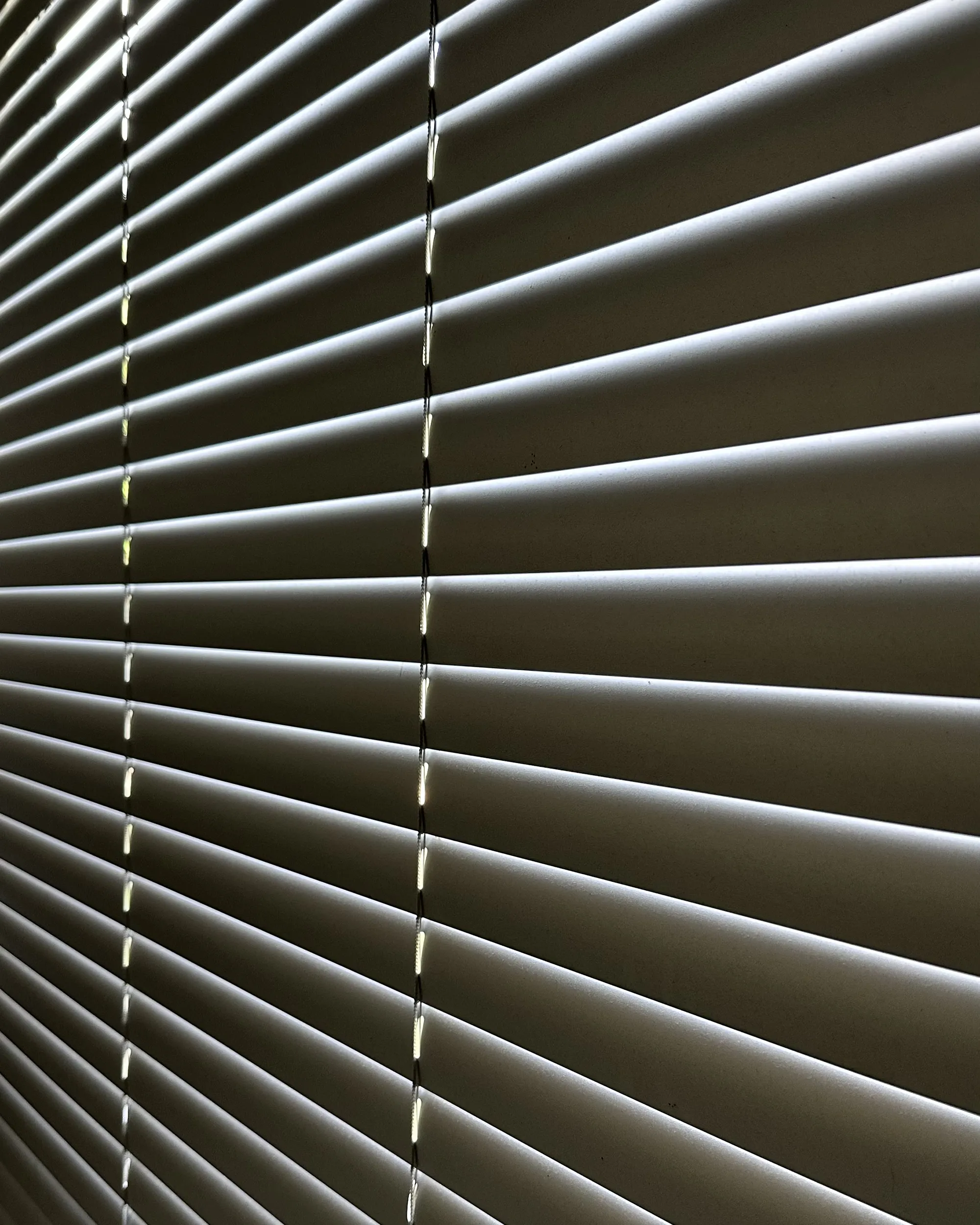 Detalhe das lâminas da persiana horizontal de alumínio 50mm prata fosca com passagem de luz entre os gomos.