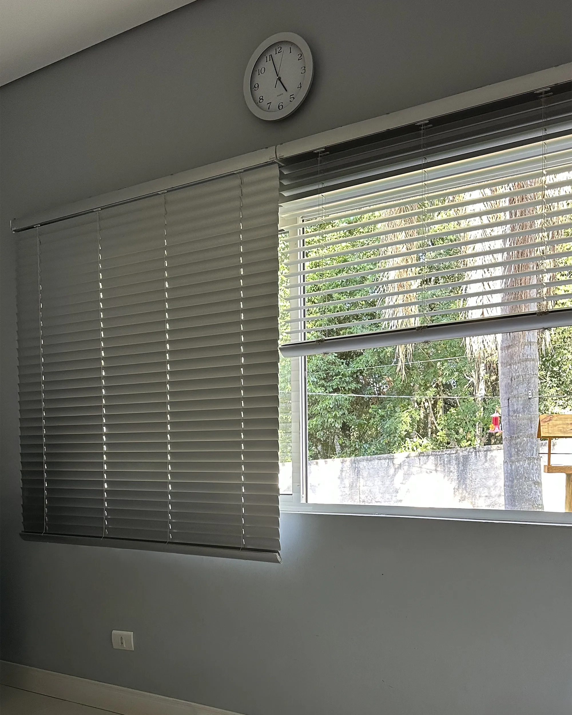 Persiana horizontal de alumínio 50mm prata fosca com lâminas inclinadas, permitindo entrada de luz e visão externa parcial.