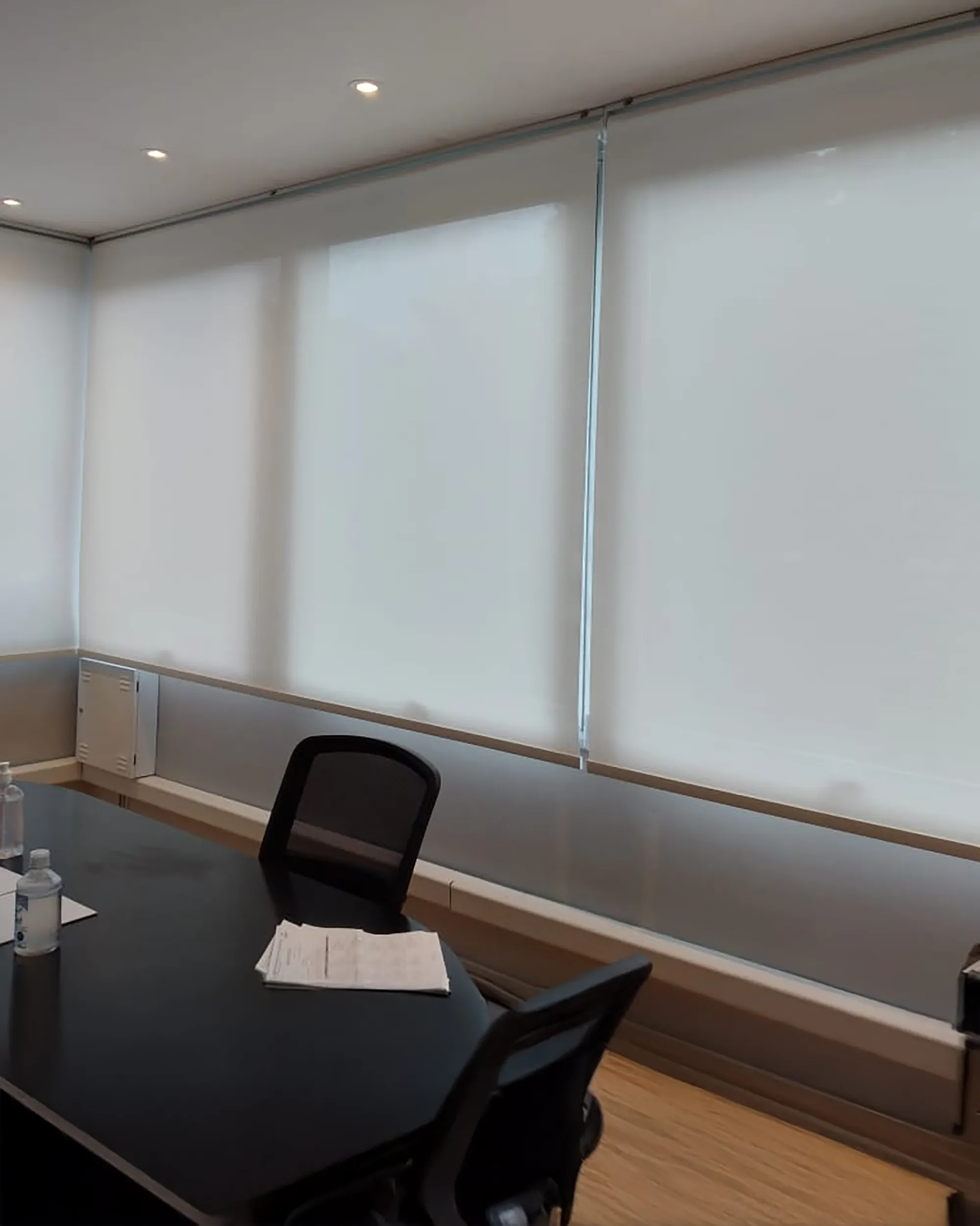 Persiana rolô tela solar 1% branca instalada em escritório, com controle de luz natural e conforto visual.