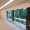 Persiana Rolô Tela Solar 1% branca instalada em grandes vãos de vidro, com vista para o jardim.
