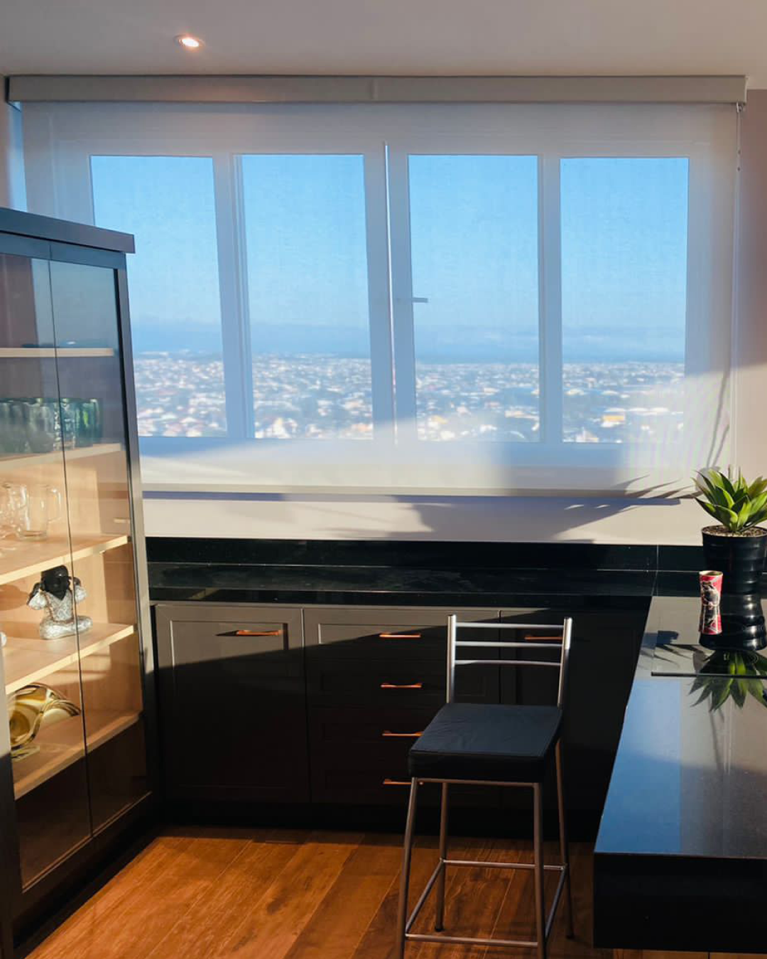 Persiana Rolô Tela Solar 5% Branca instalada em janela panorâmica, filtrando a luz natural e preservando a vista externa.