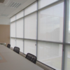 Persiana Rolô Tela Solar 5% Cinza instalada em sala de reunião corporativa, controlando a luminosidade e reduzindo o calor.
