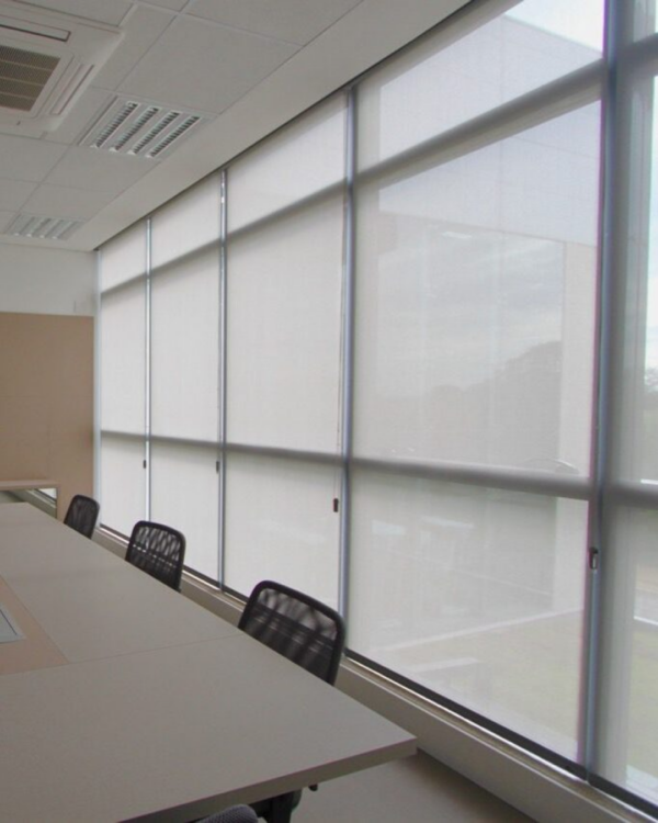 Persiana Rolô Tela Solar 5% Cinza instalada em sala de reunião corporativa, controlando a luminosidade e reduzindo o calor.