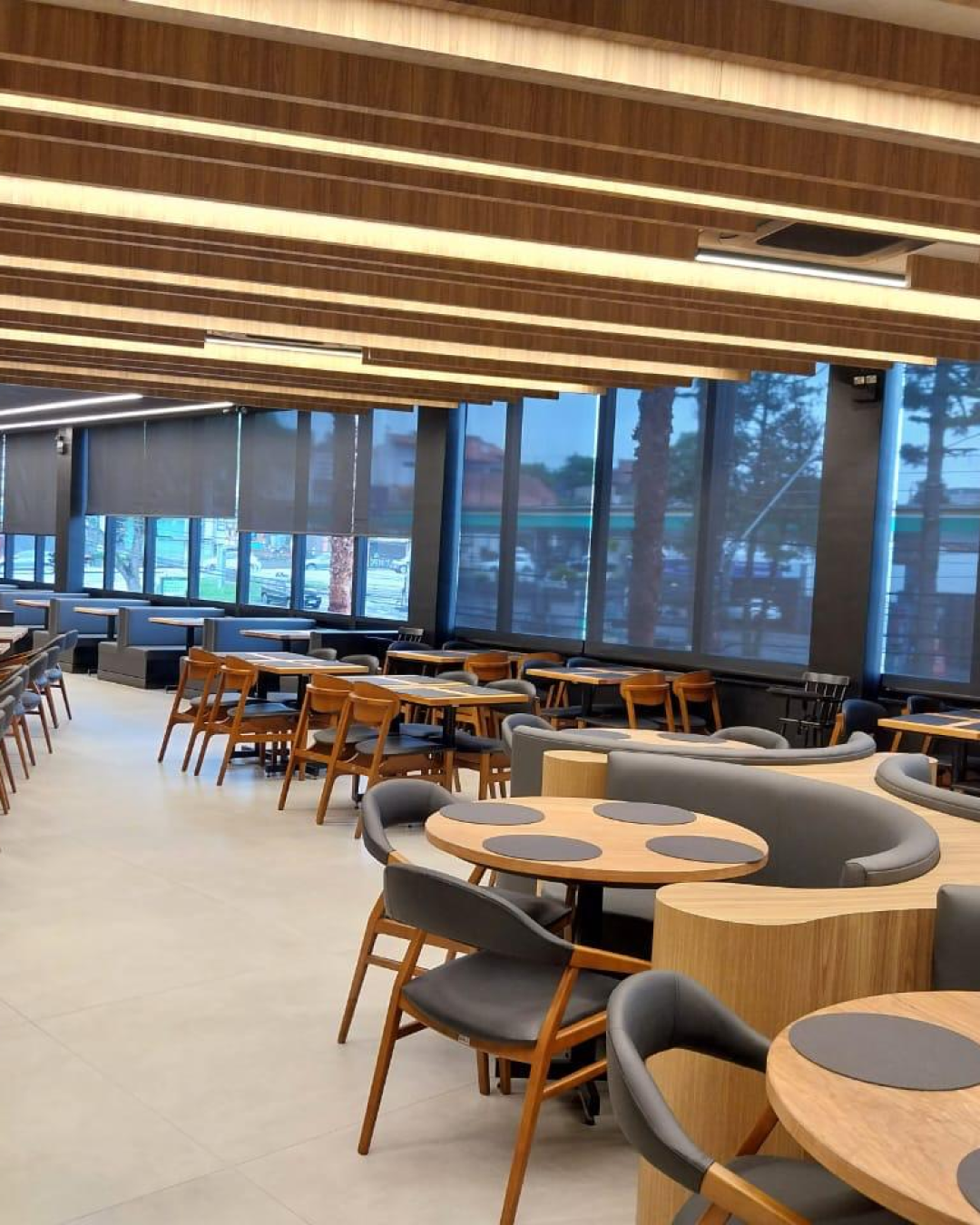 Ambiente comercial com Persiana Rolô Tela Solar 5% Preta instalada em janelas panorâmicas.